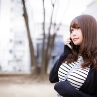 午後の天気を気にしながらスマホで通話するお散歩女子の写真