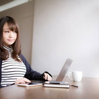 カフェで作業するノマド女子がリモートワークをしている様子の写真