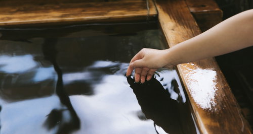 檜風呂の湯船に手を入れて源泉かけ流しの湯温を確かめる