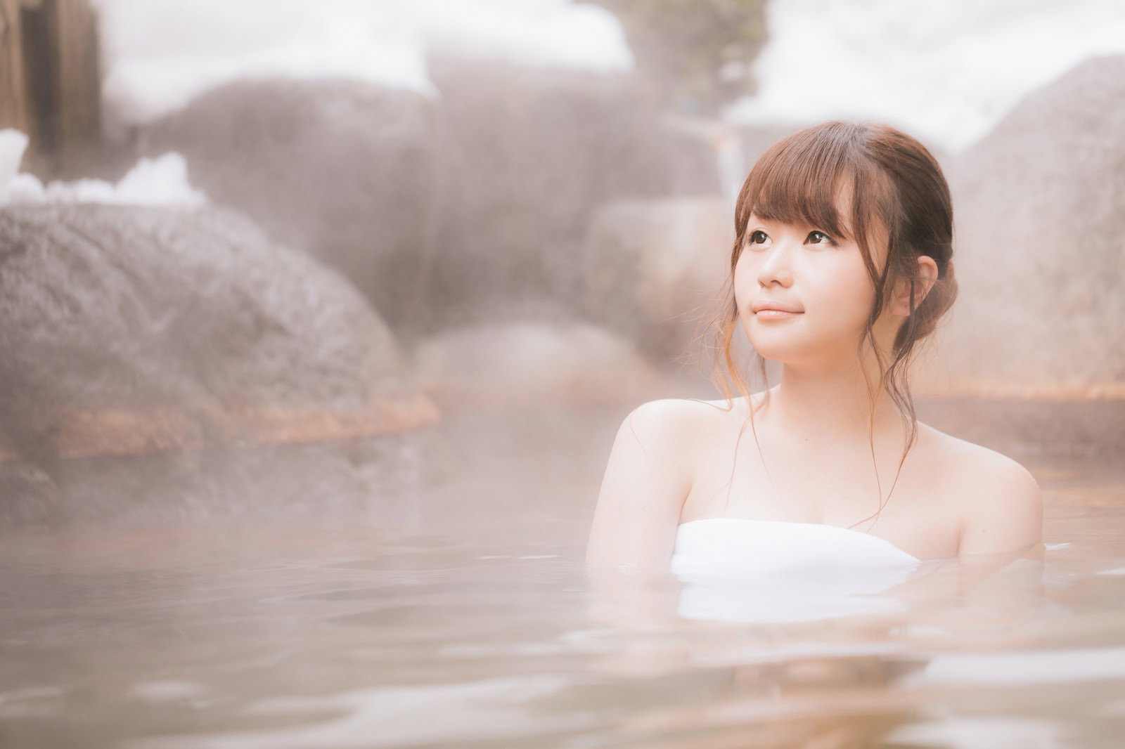 露天風呂に入る若い女性、湯けむりが立ち上る雪見温泉でリラックス［モデル：茜さや］