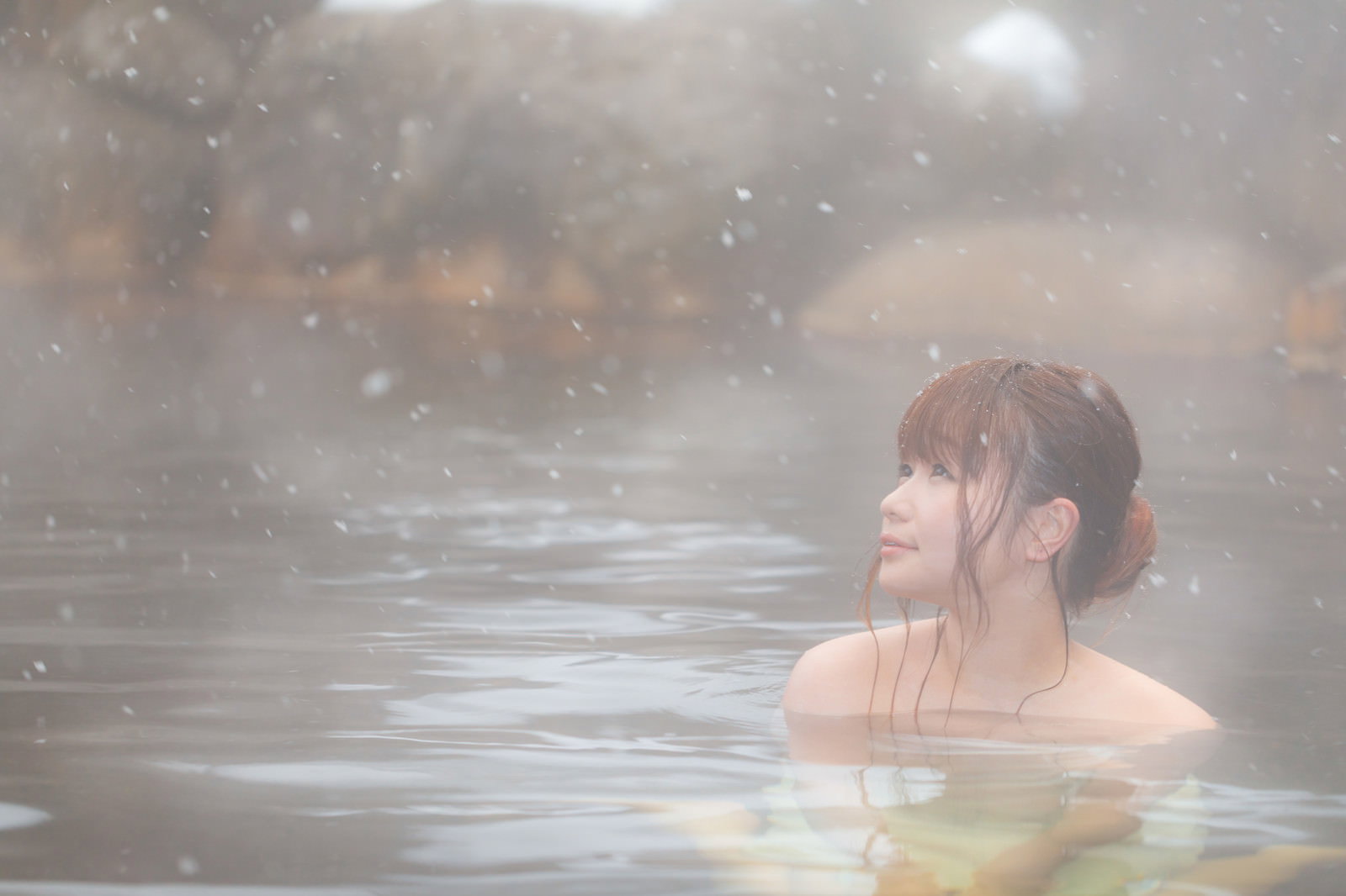 雪舞う露天風呂で微笑む女性［モデル：茜さや］
