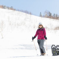 本日は平湯温泉スキー場からお送りします、スノーシューで雪山を歩む女性の写真