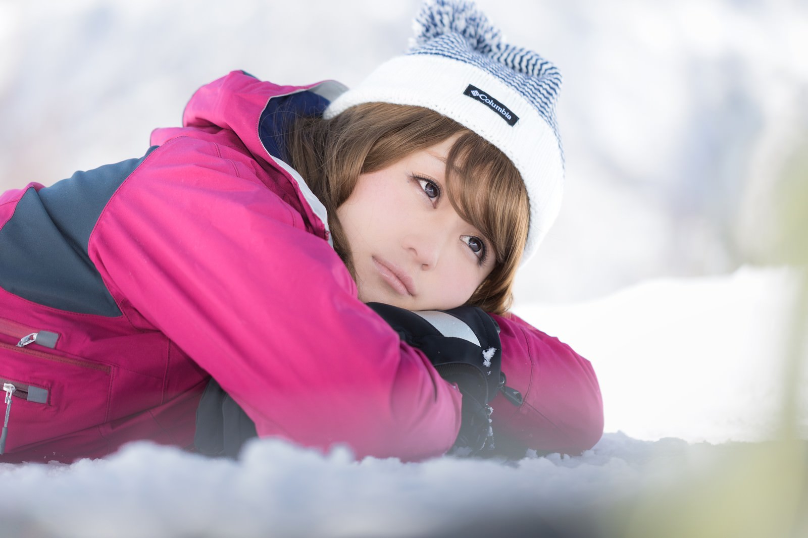 ゲレンデの雪上に寝転びこちらを向く女性［モデル：茜さや］