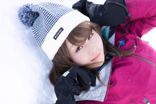 ゲレンデの天使 ピンクのスキーウェア姿で雪の上に寝そべる女性