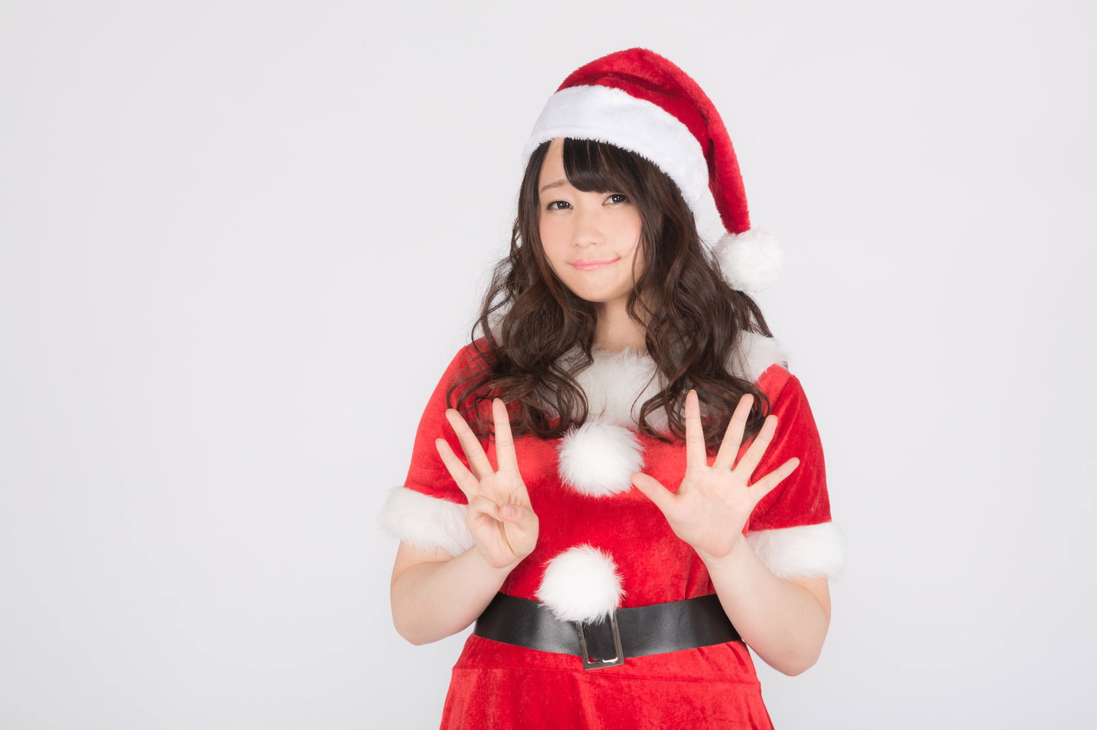 赤と白のサンタ衣装を着た女性が両手を広げて笑顔で立つ