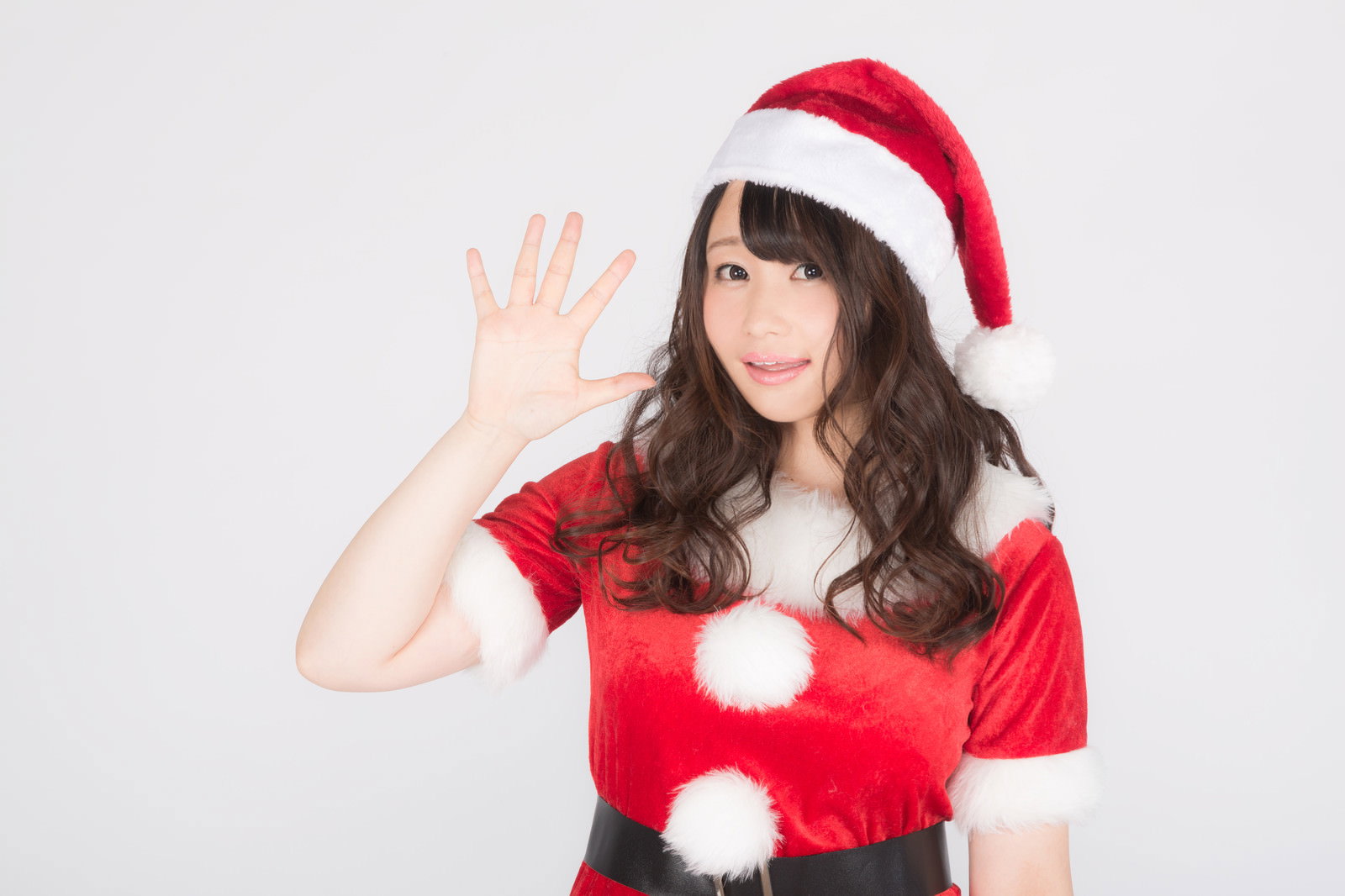サンタコスプレで片手を上げてカメラに向かって笑顔でポーズする女性［モデル：茜さや］