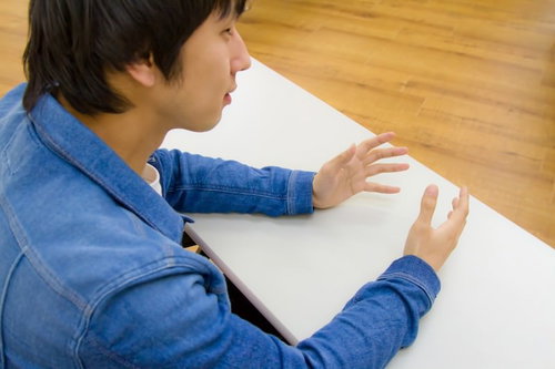 デスクに座ってろくろを回すような手つきの男性