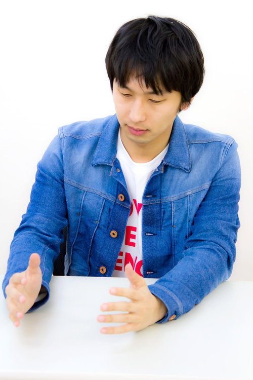 カジュアルな服装でろくろ回しジェスチャーをする青年