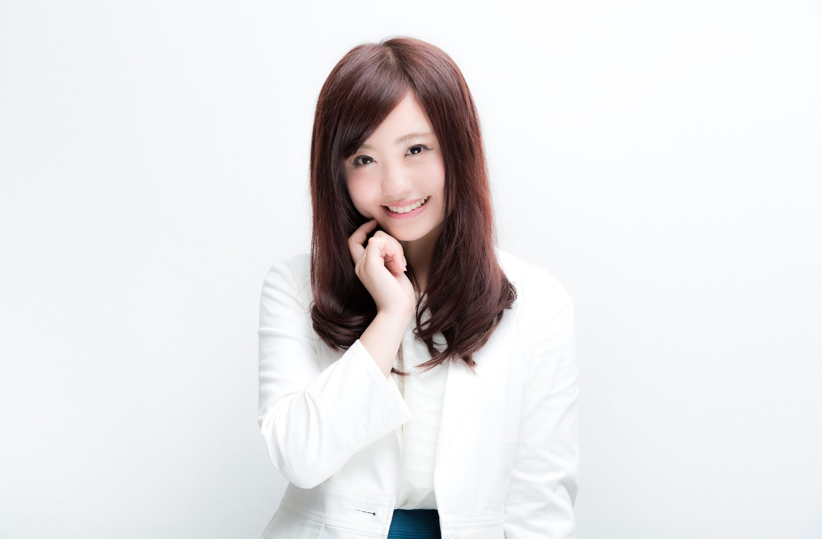 白いブラウスを着て、ほほ笑みながら両手を顔に寄せる女性［モデル：河村友歌］