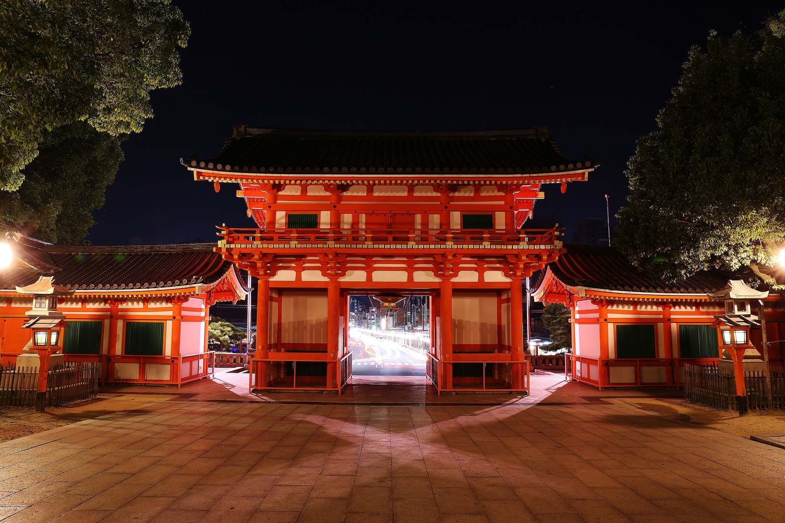 夜間にライトアップされた朱色の神社の門と境内