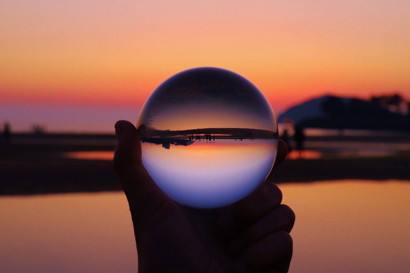 手に持った透明な水晶球に夕焼け空が反転して映り込んでいる