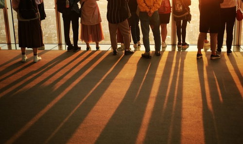 夕焼けに染まる絨毯に伸びる影と観客のシルエット