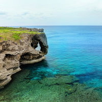 エメラルドグリーンの透明な海と切り立つ断崖絶壁の海岸の写真