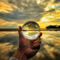 ガラス玉に映る夕焼けと浜辺の風景、反射する海岸線の写真