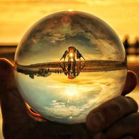 夕焼けの海岸で水晶球から覗く4人組のシルエットの写真