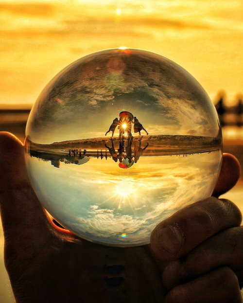 夕焼けの海岸で水晶球から覗く4人組のシルエット