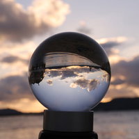 ガラス玉に映る朝焼けの海岸と雲の風景、透明な水晶球の光の反射の写真