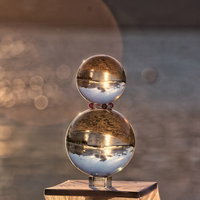 木製の台に重ねたガラス玉と湖面に煌く夕日の玉ボケの写真