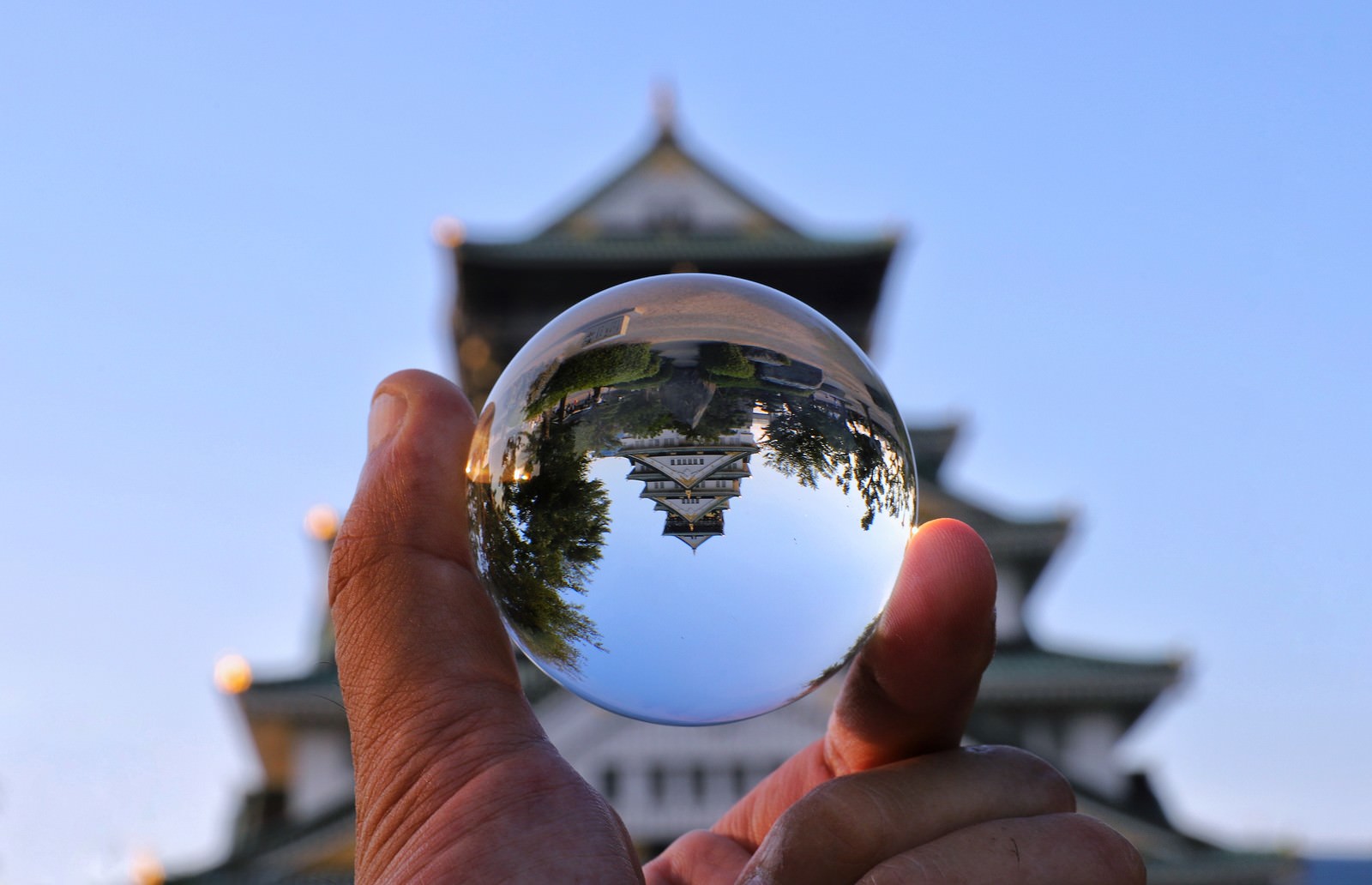 手に持った水晶球に城跡が逆さまに映り込んでいる様子