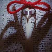 辞書の上に浮かび上がる運命のハートマークと赤い糸で結ばれた指輪の写真