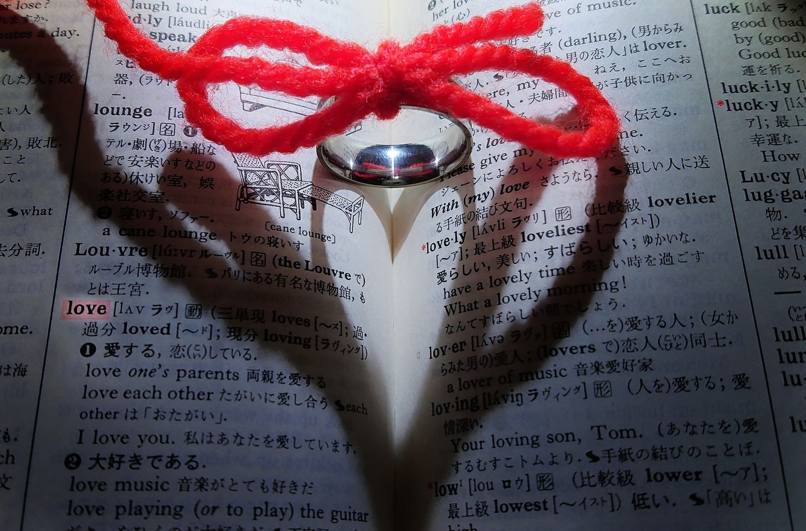 赤い糸を通した指輪がハート型の影を作っている写真