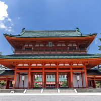 青空の下に立つ平安神宮の赤い大門の写真