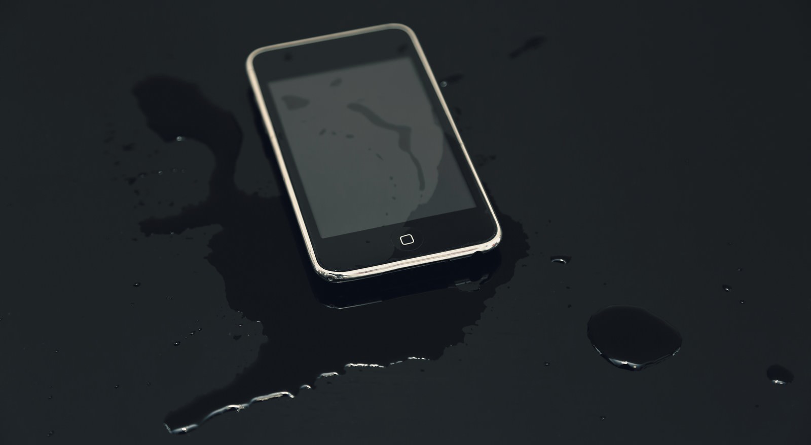 水に浸かり濡れているスマートフォンと水滴