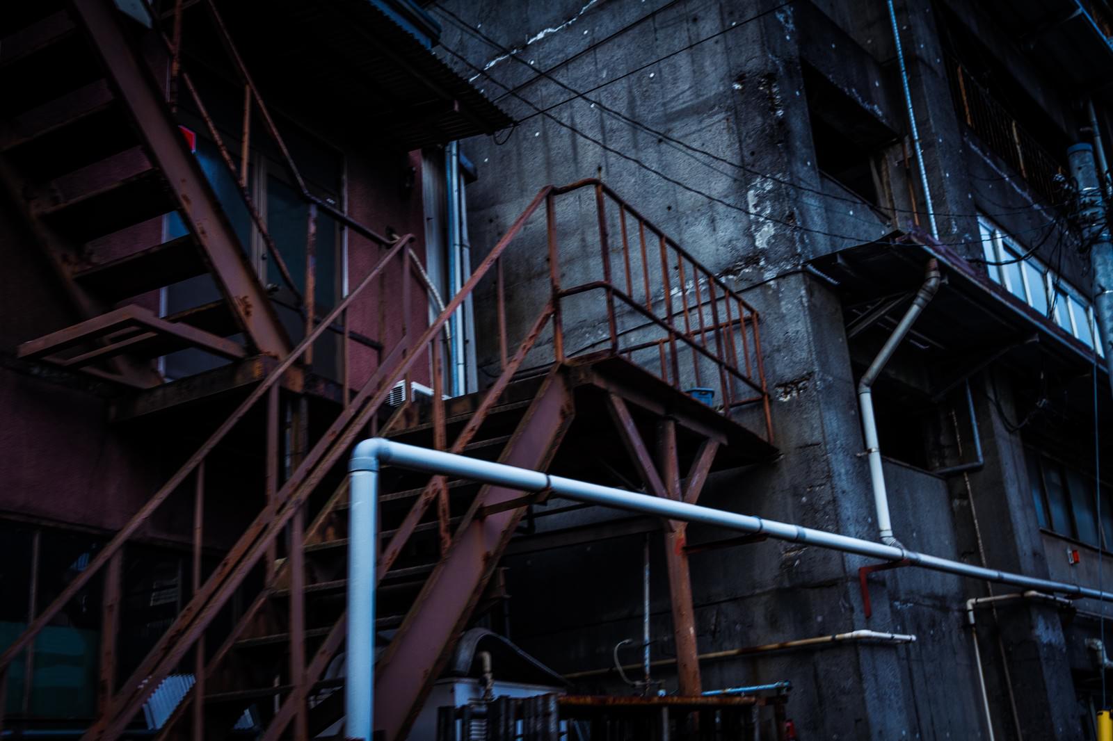 赤錆びた鉄骨階段とコンクリート壁の古い工場の夜間風景