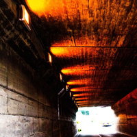 老朽化した薄暗いトンネル内部のコンクリート壁と錆びた鉄骨の写真