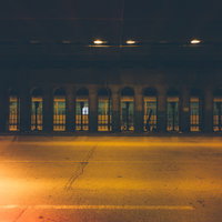 アーチ型の柱が並ぶ黄色い光のガード下の夜景の写真