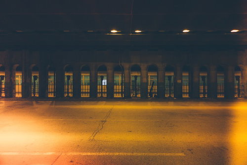 アーチ型の柱が並ぶ黄色い光のガード下の夜景