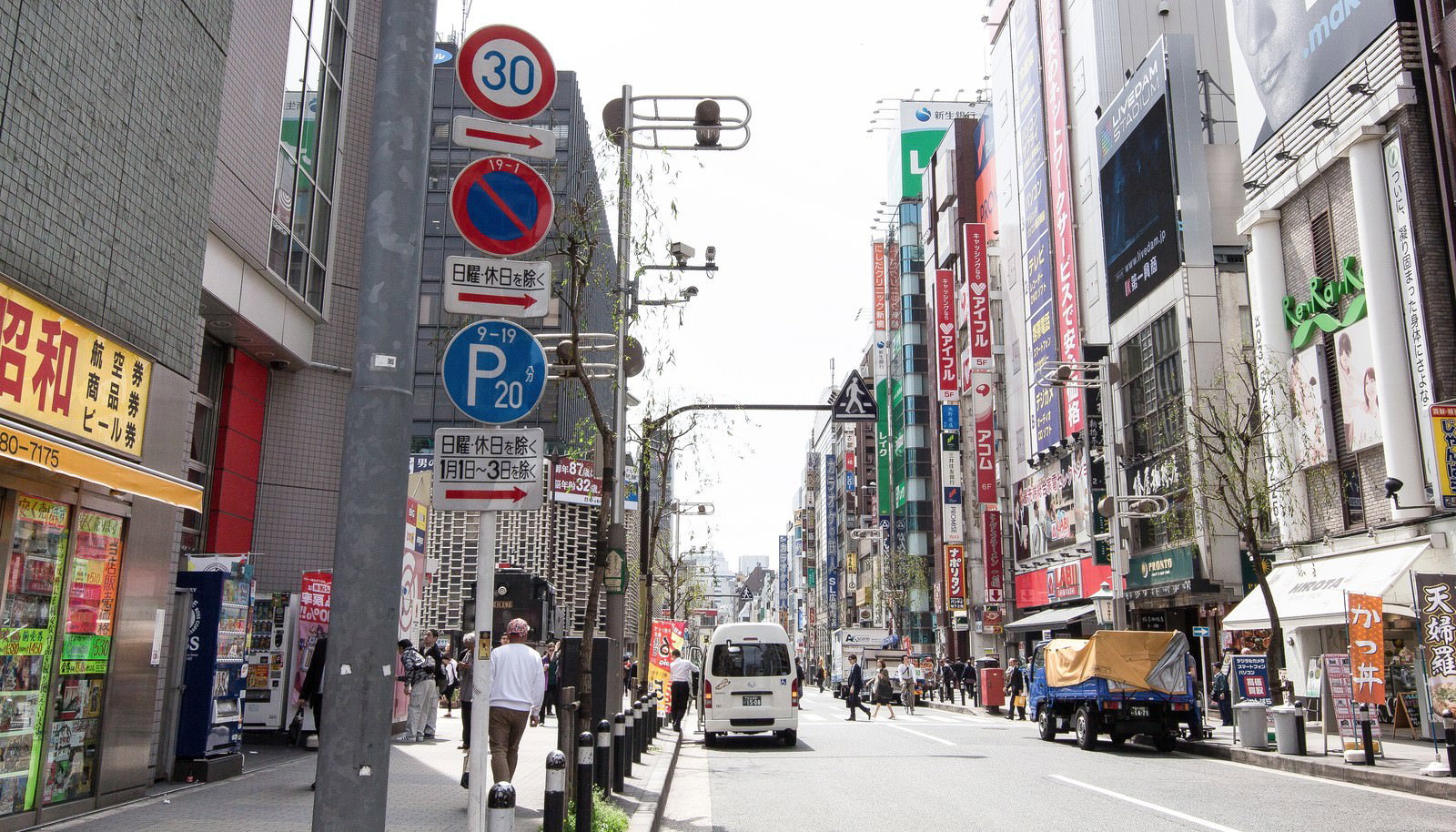東京・新橋の駅前通りで、ビルと看板が立ち並ぶ繁華街の風景