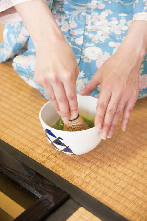 白い茶碗でお茶を点てる着物姿の手元、黒い指輪をはめた女性