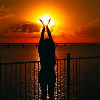 夕暮れの太陽をつかまえる女性のシルエットの写真