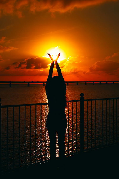 夕暮れの太陽をつかまえる女性のシルエット