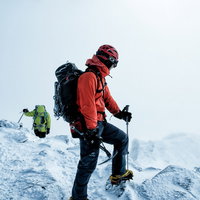 赤いジャケットの登山者が雪山で下山路を見つめるの写真