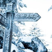 吹雪いた雪で凍り付いた登山道の標識と冬山の過酷な環境の写真