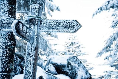 吹雪いた雪で凍り付いた登山道の標識と冬山の過酷な環境