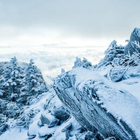 凍り付く山肌と眼下に広がる雲海の冬山風景の写真