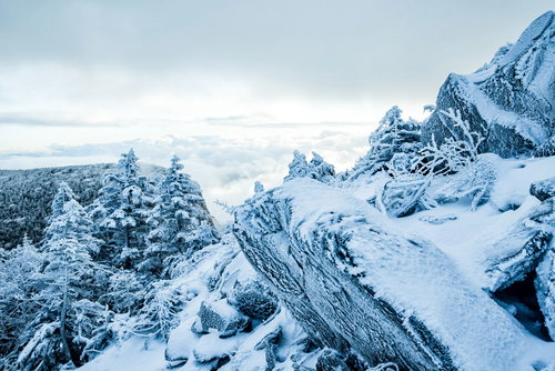 凍り付く山肌と眼下に広がる雲海の冬山風景
