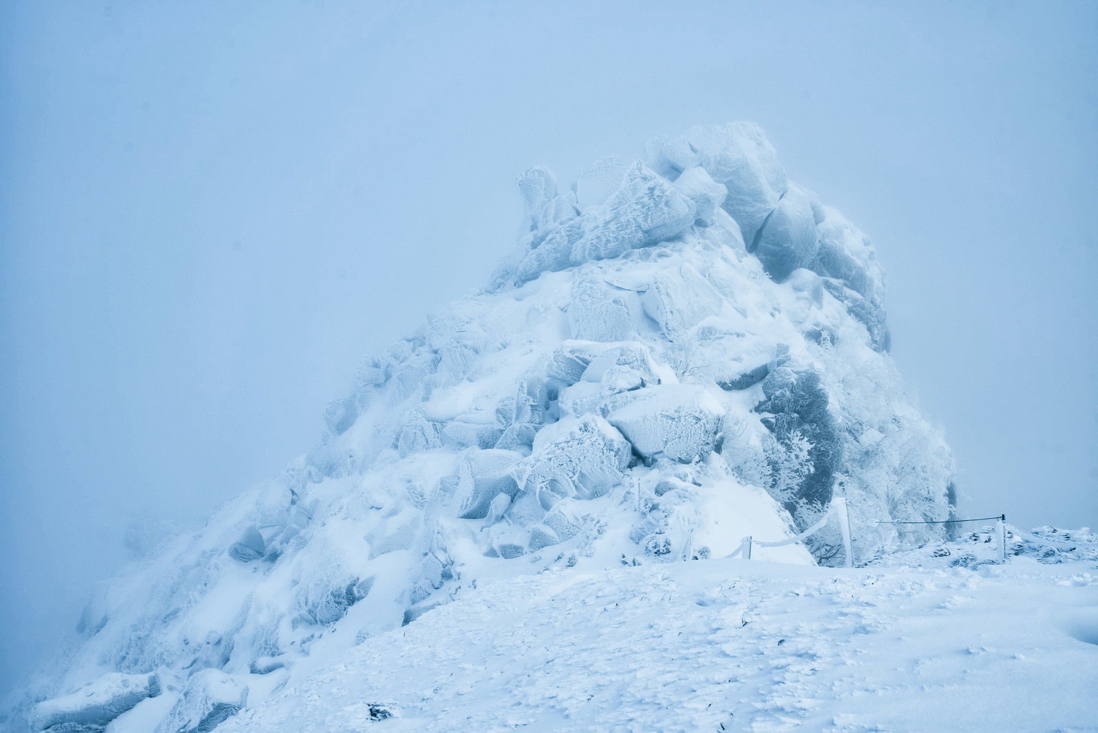 雪に覆われた岩峰が吹雪の中で霞む冬山の風景