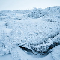 厳冬の岩肌に付着した小さな樹氷と雪の結晶の写真