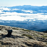 硫黄岳の山頂付近にある祠と雲海に包まれた八ヶ岳連峰の写真