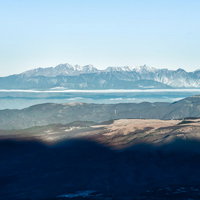 霞む空と遠くに見える北アルプスの山峰と積雪風景の写真