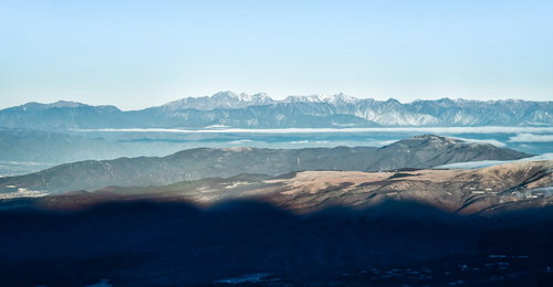 霞む空と遠くに見える北アルプスの山峰と積雪風景