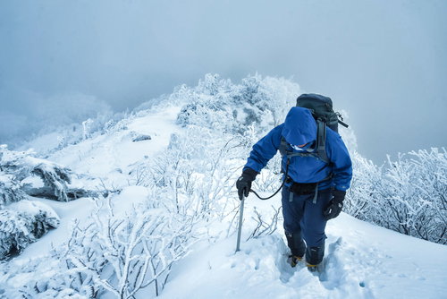 雪化粧した雪山の雪深い登山道で山頂を目指す登山者