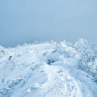 積雪の登山道に残る登山者の足跡と冬景色の写真
