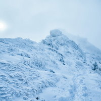 立ち込めるガスに隠れた太陽と積雪の稜線の写真