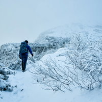立ち込めたガスで隠れる山頂を目指す積雪の登山者の写真