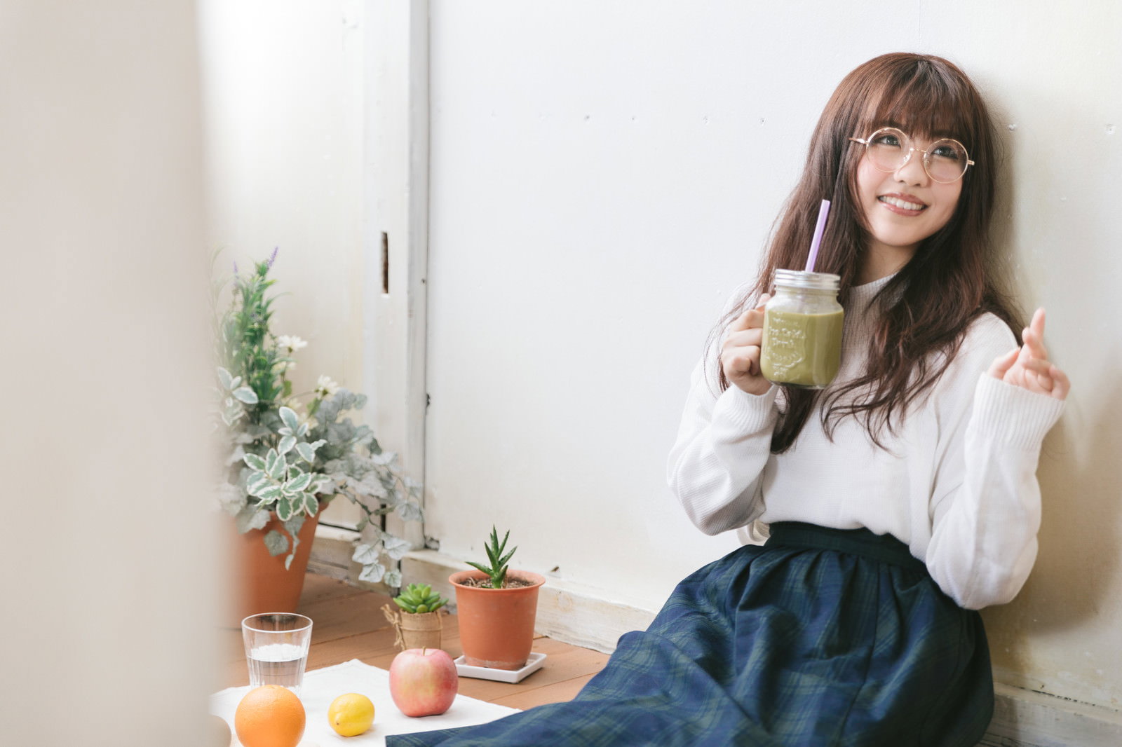 グリーンスムージーを手に持って笑顔を見せる眼鏡の女性［モデル：河村友歌］